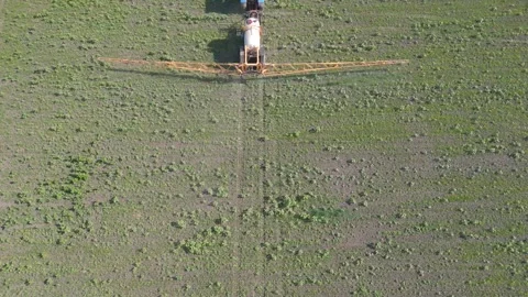 A crop sprayer operates in a vast green field, distributing liquid across the Vídeo Stock 285186901