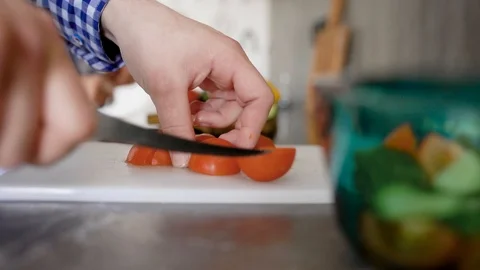 Crop unrecognizable man standing at table on kitchen and chopping tomato on Stock Footage 88237922