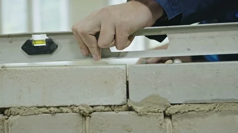 Crop view of building checking brick wall with leveling board while working. Stock Footage 97742994