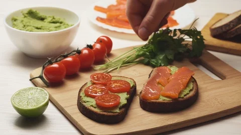 Crop view of chef decorating parsley leaves with avocado sandwiches. Vidéo 104721082