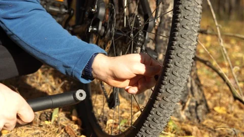 Crop view of a cyclist with a hand pump inflates the rear wheel of a bicycle. Stock Footage 127349052