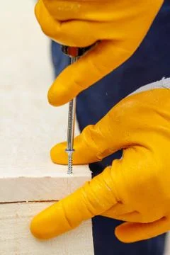 Crop view driving self-tapping screw into chipboard placed on wooden workbenc Stock Photos