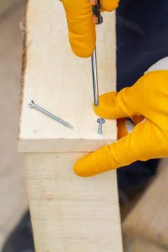 Crop view driving self-tapping screw into chipboard placed on wooden workbenc Stock Photos