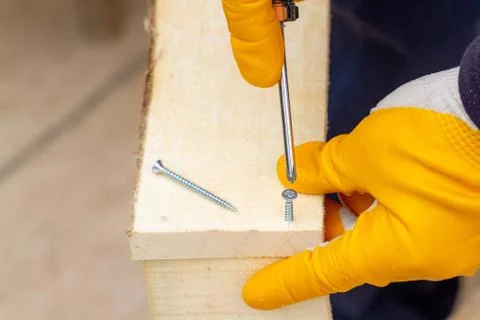 Crop view driving self-tapping screw into chipboard placed on wooden workbenc Stock Photos