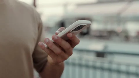 Crop view of Hispanic man hand texts on modern smartphone on city street Stock Footage 308038129