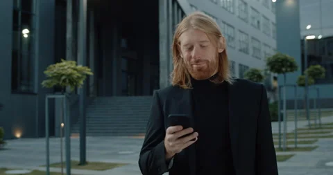 Crop view of long haired man in 30s smiling and looking at smartphone screen Stock Footage 142991282