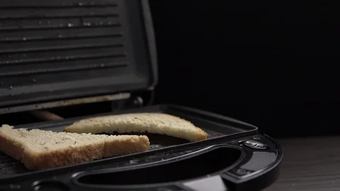 Crop view of man cooking toasts of white bread in electric grill at table Vidéo 104100395