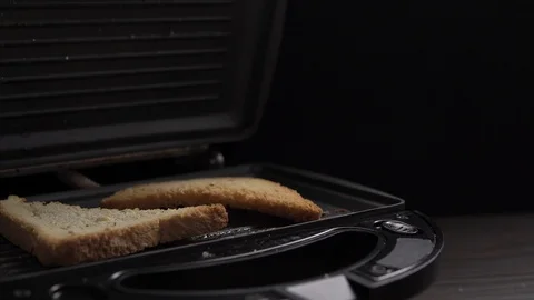 Crop view of man cooking toasts of white bread in electric grill at table Vidéo 104100508