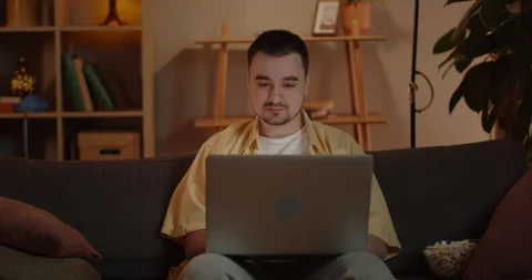Crop view of man freelancer using laptop while sitting on couch at home Stock Footage 151698068
