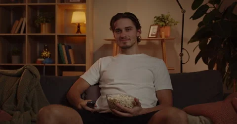 Crop view of man taking remote controller and switching on tv. Caucasian bearded Stock-Footage 234101072