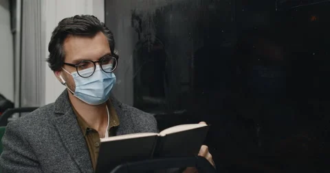 Crop view of smart man in protective mask turning book page while sitting in Stock Footage 147663311