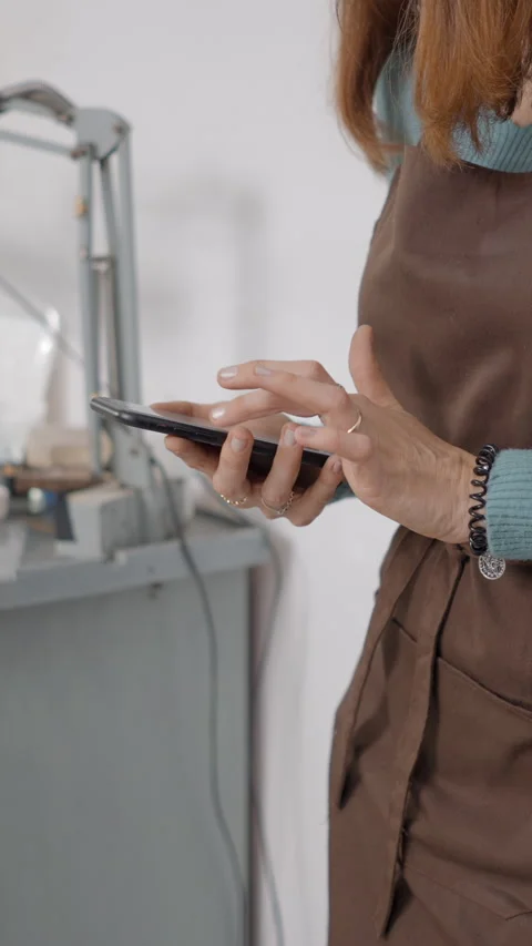 Crop View Of Young Artisan Browsing On Her Smartphone Inside Her Working Place Stock Footage 265965513