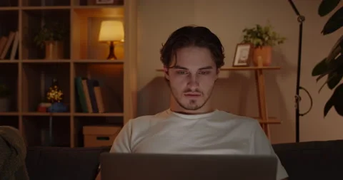 Crop view of young man freelancer using laptop while sitting on couch at home Stock Footage 149974006