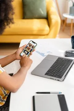 Crop woman using smartphone while working on laptop at home and ordering food Foto stock