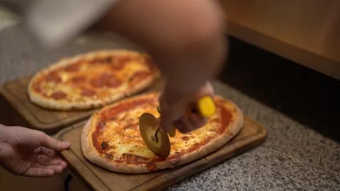 Crop worker slicing appetising pizza in restaurant's kitchen Stock Footage 241484366