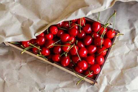 Cropped box, crape of dark red sweet cherries with tail on craft wrinkled pap Фото