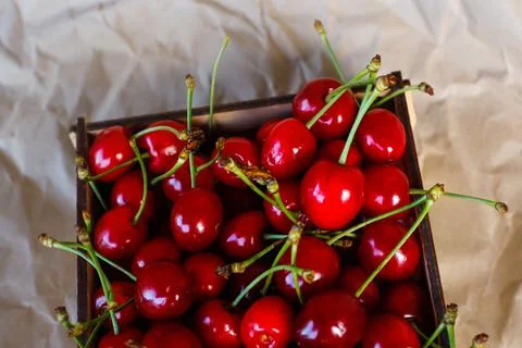 Cropped box, crape of sweet red cherries with tail and leaves on craft wrinkl 写真素材