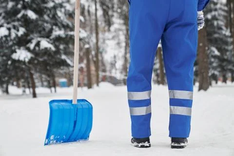 Cropped cleaner with shovel on snow in park. Stock Photos