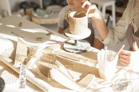 Cropped close up of a ceramic mug being made by woman and young boy Stock Photos
