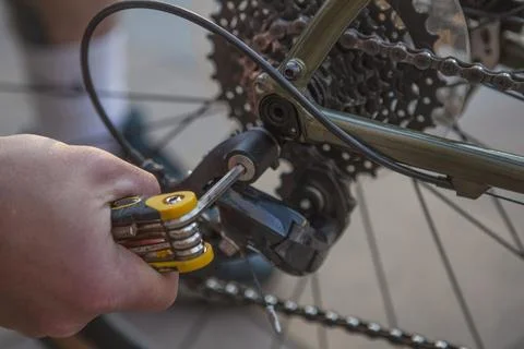 Cropped close up of a man using multitool screwdriver, fixing his bicycle Stock Photos