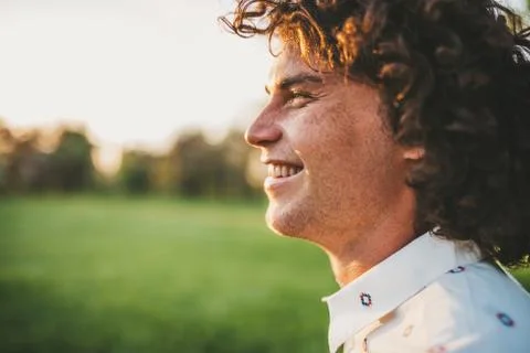 Cropped close up side view shot of handsome happy young freckled male smiling Stock Photos