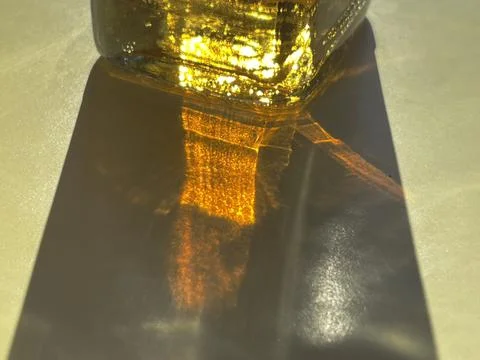 Cropped close up of sunlight shining through bottle with yellow liquid Stock Photos