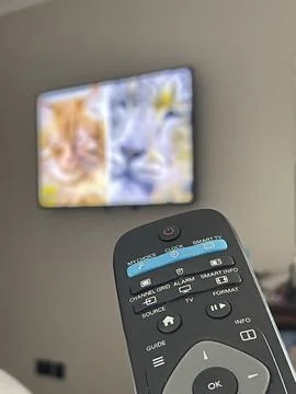 Cropped close up of tv remote control, blurred television on the backgrund Stock Photos