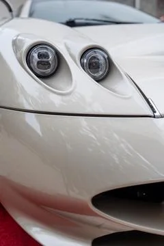 Cropped front part of pagani with two headlights with white glass. Selective Stock Photos