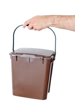 Cropped hand holding a brown plastic organic waste bin isolated on a white ba Stock Photos