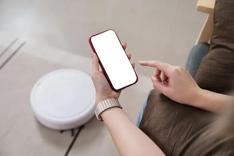 Cropped hand using smartphone to control smart robot vacuum Stock Photos