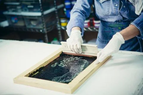 Cropped hands of craftswoman using squeegee to print design on fabric Foto stock