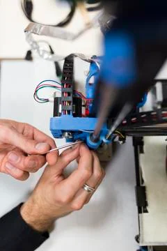 Cropped hands of engineer fixing 3D printer on table in office Stock Photos