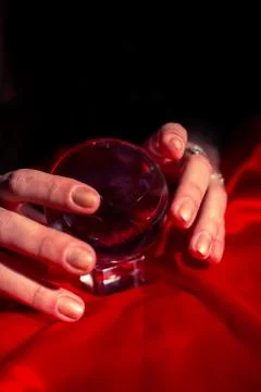Cropped hands of fortune teller using red crystal ball Fotos de archivo