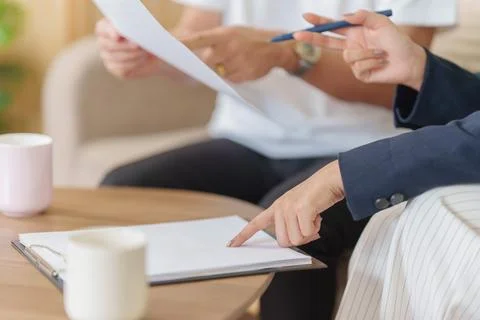 Cropped hands pointing at document on clipboard for contract agreement and Stock Photos