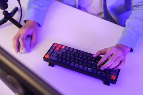 Cropped hands typing on mechanical keyboard and using mouse at gaming desk Stock Photos