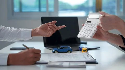 Cropped hands using calculator over car loan contract for auto insurance finance Stock Photos