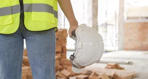 Cropped image of architect in yellow vests standing holding safety helmet sta Stock Photos