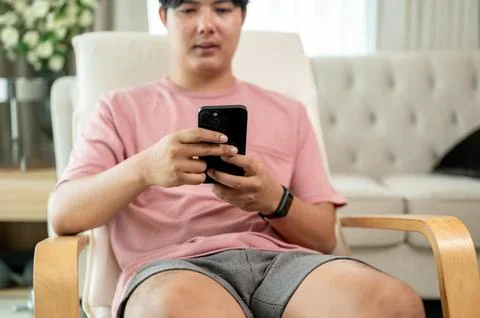 A cropped image of an Asian man is using his smartphone on a lounge chair i.. Stock Photos