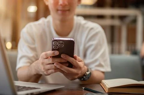 A cropped image of an Asian man using his smartphone while sitting in a cof.. Stock Photos