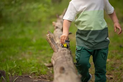 Cropped image of a boy of 3 years old playing with a toy car on a log Stock-Fotos