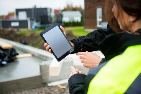 Cropped Image Of Carpenter Showing Digital Tablet To Colleague 写真素材