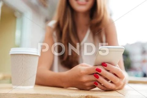 Cropped image of charming young woman using smartphone in cafe Stock Photos