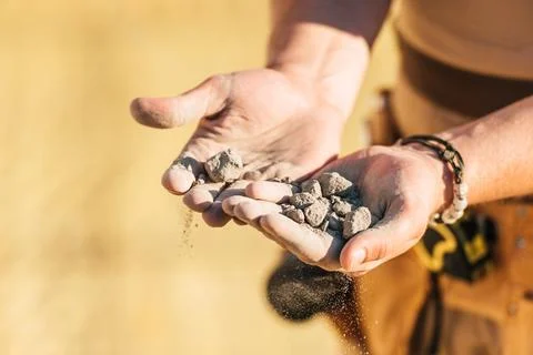 Cropped image of construction worker holding stones in hand palms Stock Photos