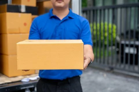 A cropped image of a delivery guy standing at the back of his truck, carryi.. Stock Photos