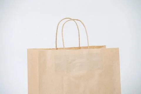 Cropped image of empty brown paper bag with rope handles over white background Stock Photos