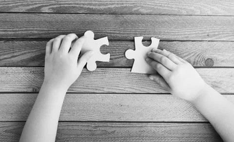 Cropped image of hands connecting two puzzle pieces on wooden ta Foto stock