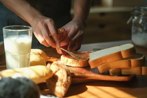 Cropped image of man making sweet sandwich and spreading  strawberry jam on.. Stock Photos