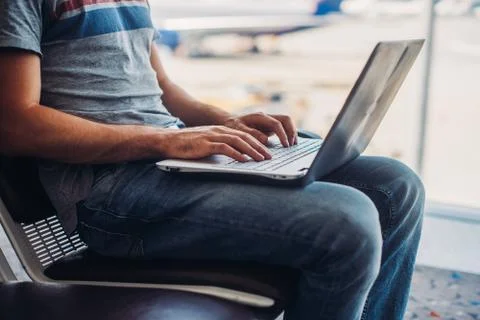 Cropped image of a man using laptop to write emails in airport terminal 写真素材