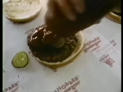 Cropped image of man's hand adding tomato sauce in burger Stock Footage 260258076