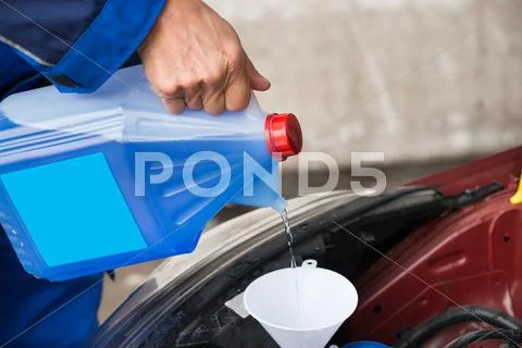 Cropped image of mature serviceman pouring windshield washer fluid into car a Stock Photos